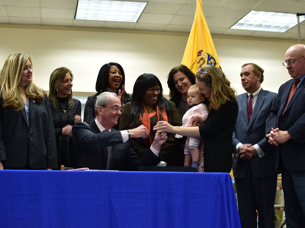 2019-NJ-PFML-expansion-pen-handoff-Gov-Murphy-to-Yarrow-and-child-resized