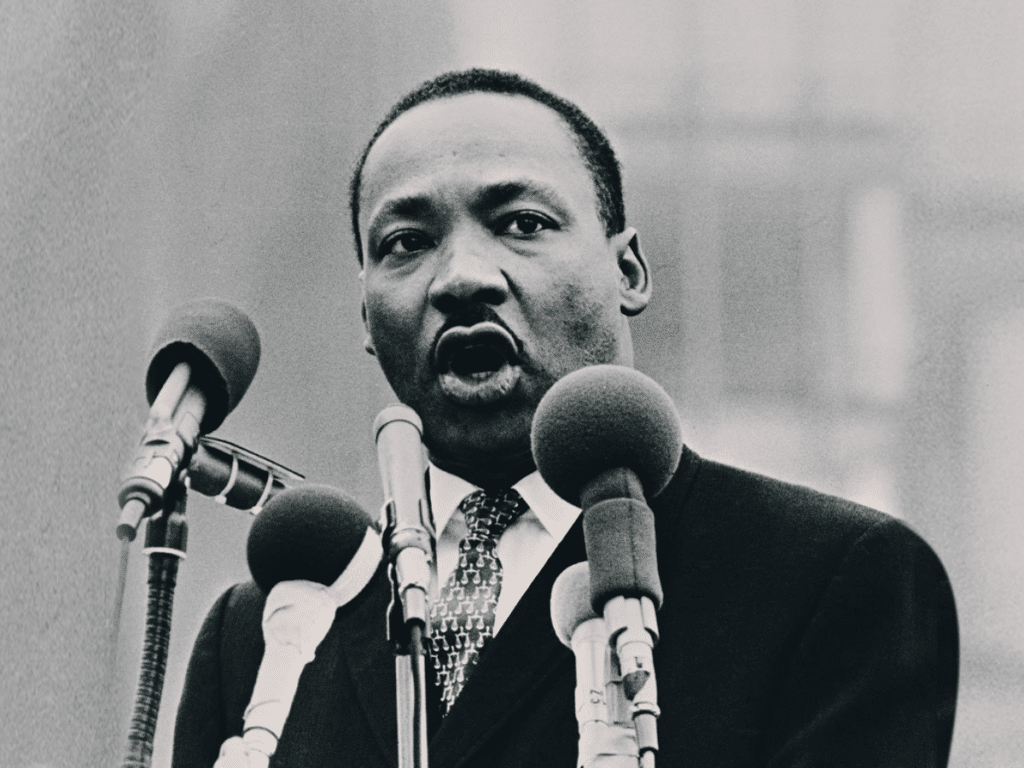 Martin Luther King Jr. giving a speech at a podium with microphones.