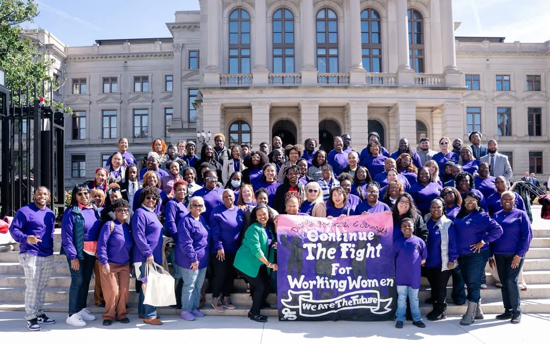 A group picture in front of Georgia State Capitol of women holding a sign that says "Continue the Fight for Working Women" "We are the Future"